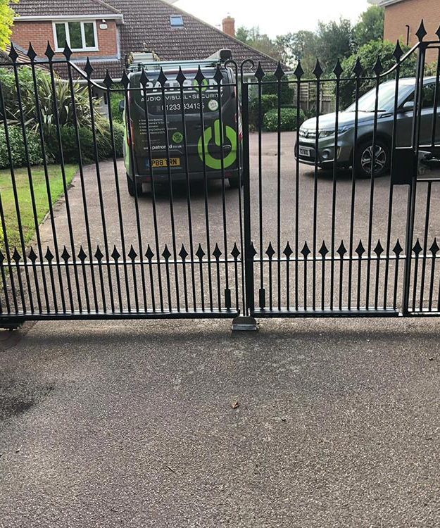 A black wrought iron gate in front of a house - Patron Security Ltd