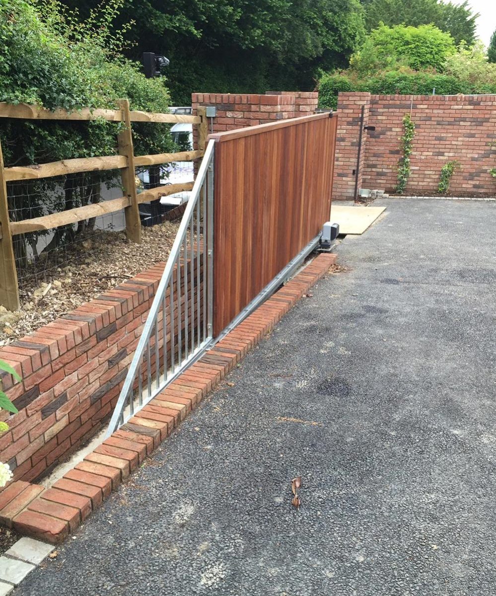A wooden gate on a driveway with a brick wall - Patron Security Ltd
