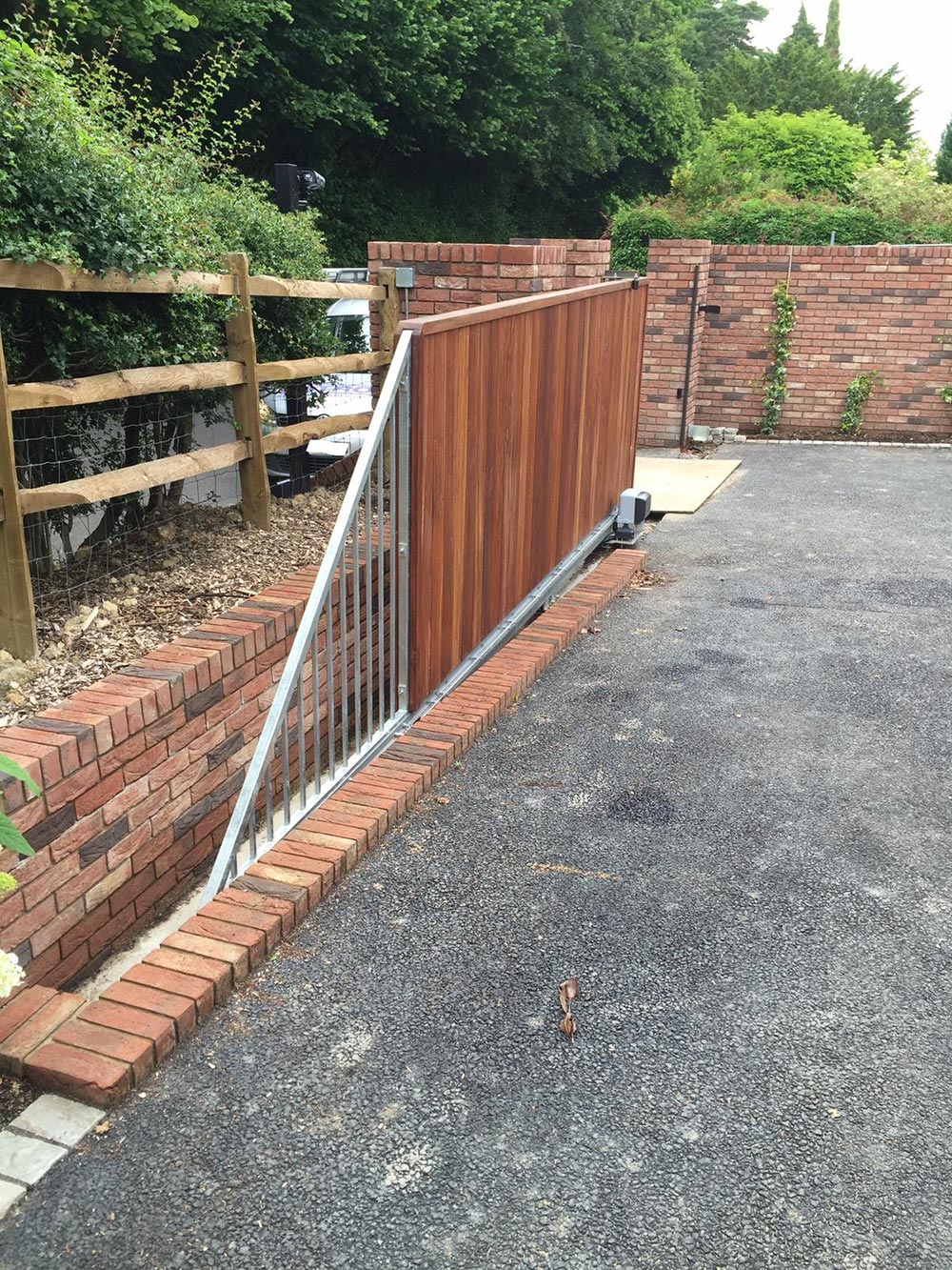 A wooden gate on a driveway with a brick wall - Patron Security Ltd